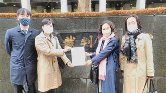東京地方裁判所前で控訴状を手にする原告の小野さん、西川さん、弁護団の上杉さん、沢崎さん