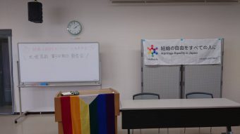 ホワイトボードに「結婚の自由をすべての人に北海道訴訟　札幌高裁　第３回期日
　報告会」と書かれている。「結婚の自由をすべての人に Marriage Equality in Japan　北海道訴訟原告弁護団」と書かれた旗が掲げられている。