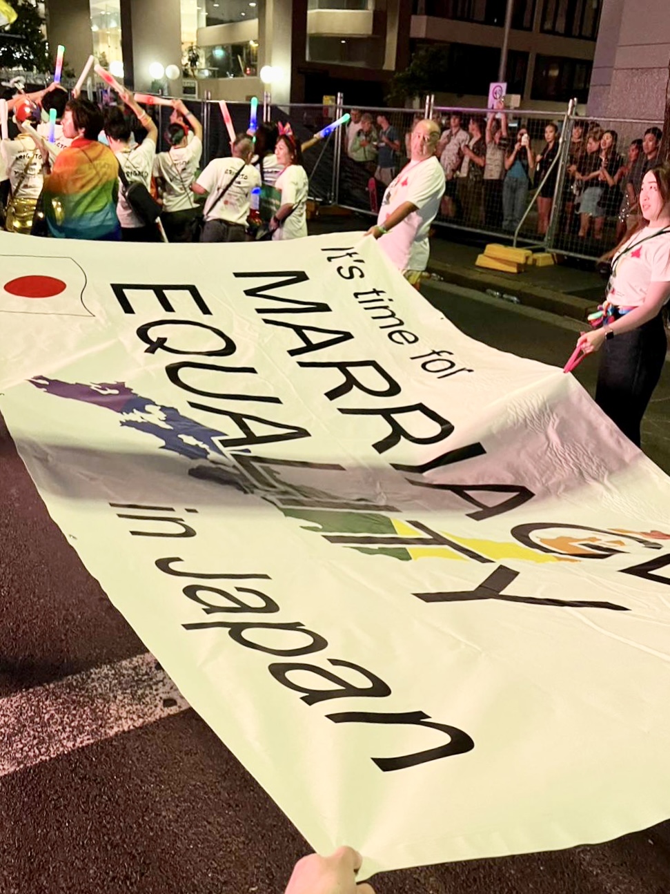 「シドニー・ゲイ＆レズビアン・マルディグラ」パレードに参加し、「MARRIAGE EQUALITY in Japan（日本でも結婚の平等を！）」というスローガンフラッグを掲げるエヴァン・ウォルフソンさんと日本からの参加メンバー