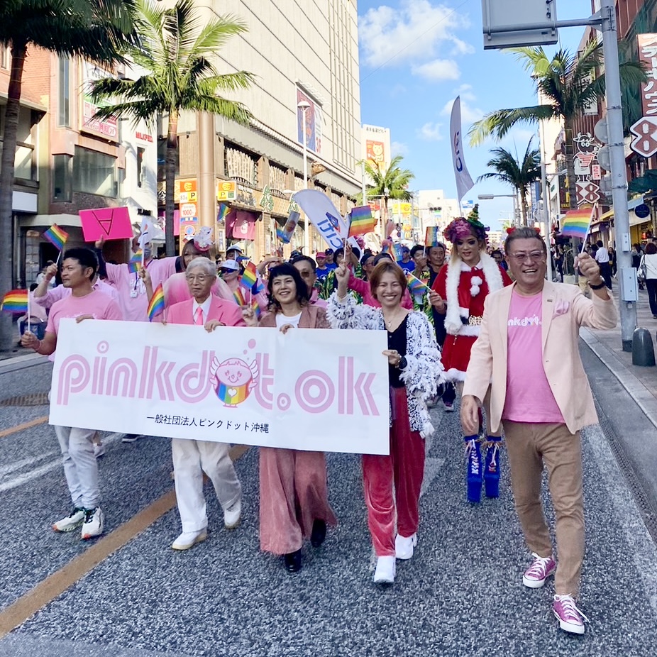 2023年12月10日（日）に沖縄県那覇市で開催されたピンクドット沖縄2023のパレード戦闘隊列。「pinkdot.ok」のバナーフラッグやレインボーフラッグを掲げて国際通りを歩いている。