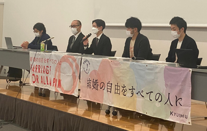 期日報告会の様子。壇上に並ぶ原告と弁護団