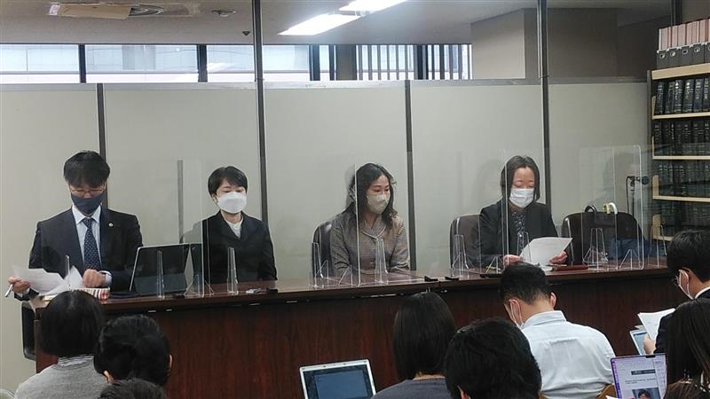 霞が関の司法記者クラブで記者会見に臨む原告の小野さん、西川さん、弁護団の上杉さん、沢崎さん。大勢の記者を前にして机に座っている