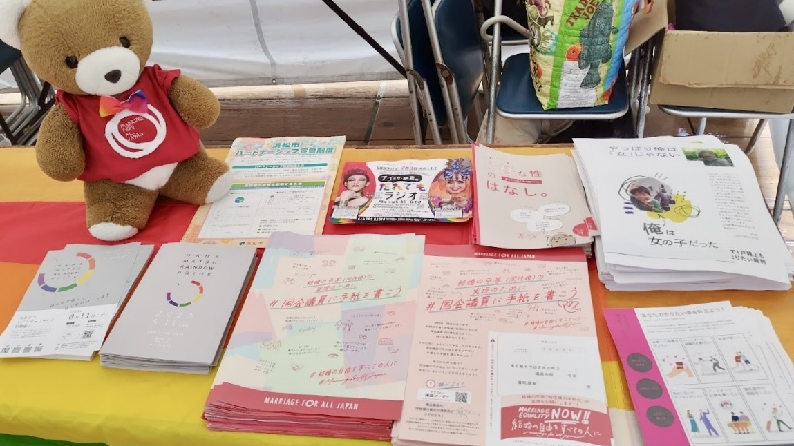 テーブルの上に、浜松レインボープライドのパンフレットや、マリフォーの「国会議員に手紙を書こう」チラシ、オペなしで戸籍上も「俺」になりたい裁判のチラシ、浜松市のパートナーシップ宣誓制度の案内などが並んでいる