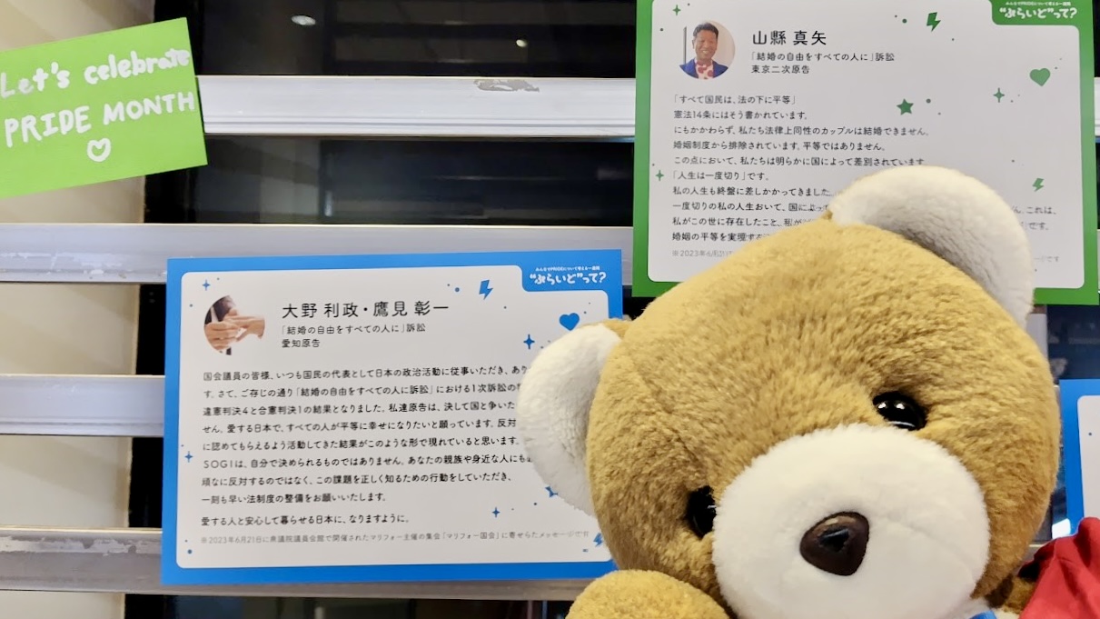 壁にたくさんのメッセージカードが飾られていて、その前でくまが嬉しそうにしている。 くまのそばには、結婚の自由をすべての人に訴訟の愛知原告さんのメッセージや、東京２次原告山縣さんのメッセージが飾られている。