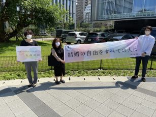 横断幕やプラカードを持って傍聴に来られた方をお迎えする弁護団員