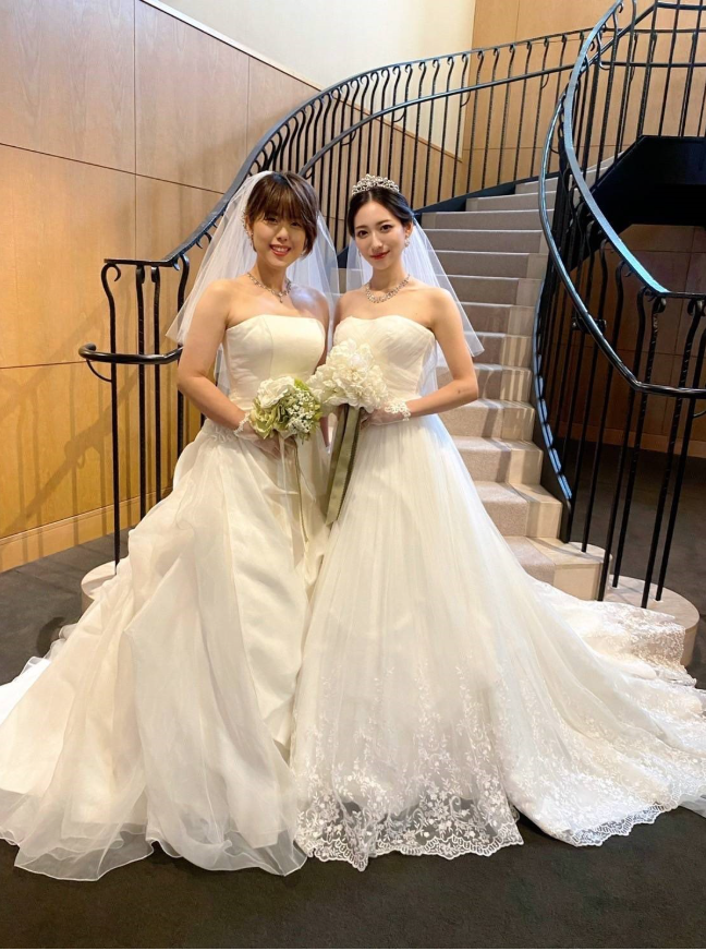 白いウエディングドレスを着た女性２人が並んで笑顔を向けている写真 