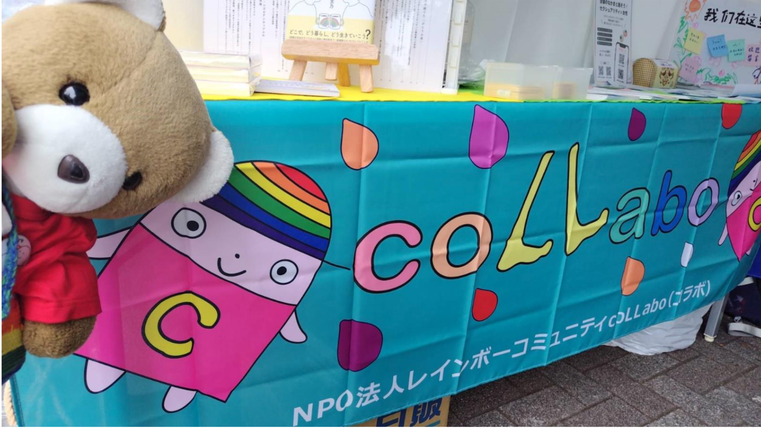 「coLLabo」と書かれた横断幕をながめるくまちゃん