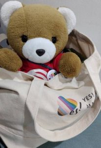 結婚の平等にYES！キャンペーンのロゴが描かれたかばんにくまちゃんが入って、来年のおでかけを楽しみに待っている。